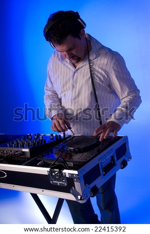 DJ by the mixing deck. Blue gel over background light.