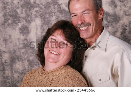 Portrait of a middle aged couple.  They are both laughing.