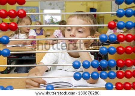 Photo shows a school boy in a math lesson. He is bored.