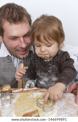 Father and son are baking for christmas. Both have flour in their faces. Studio with white background