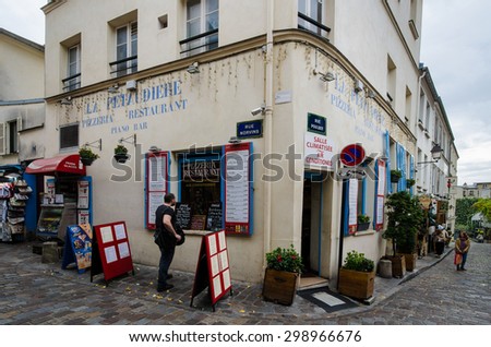 PARIS, FRANCE - OCTOBER 16, 2014: Man checks the menu La Petaudiere on the corner of Rue Norvis and Rue Poulbot, one of dozens of restaurants catering in tourists in the historic Montmartre district.