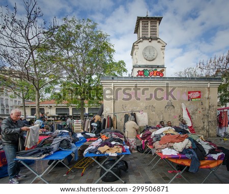 PARIS, FRANCE - OCTOBER 23, 2014: A man checks out a pair of pants through a pile of clothing at the popular flea market at the historic Place d\' Aligre in the Bastille district.