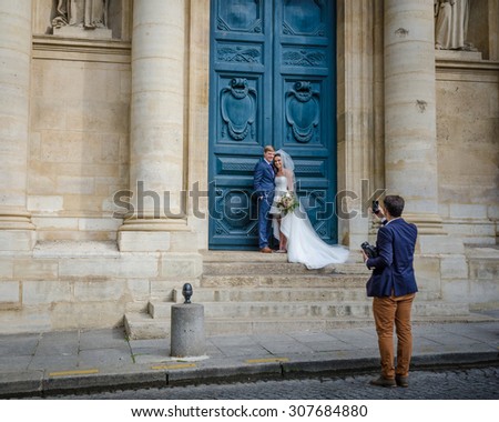 PARIS, FRANCE - AUGUST 18, 2015: Photographer takes photos of a newly-wed couple in front of Eglise de la Sorbonne in the Latin Quarter of the city.