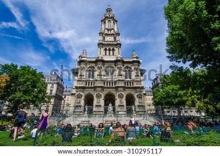 PARIS, FRANCE- AUGUST 10, 2015: People are relaxing during their lunch hour at Sainte-Trinite Square where the parish church is under renovation.