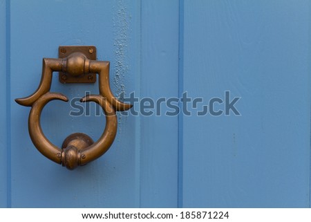 Close up of door handle with an old double wood door painted with blue
