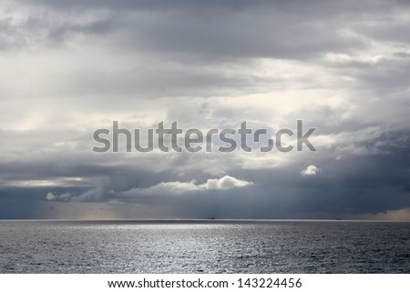 Silver seascape with dark clouds gathering in late afternoon in early winter at Bunbury\'s Ocean Beach in Western Australia.