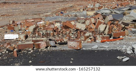 A pile of old broken  red clay brick rubble after demolition of an old building  lies on the ground  on a building  site.