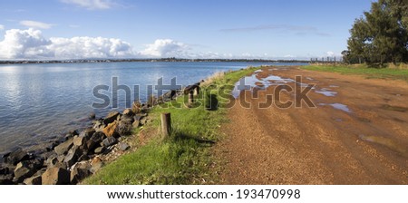 Panorama of water puddles in the gravel road  near    the calm waters of the Leschenault Estuary  near Australind Western Australia on an early morning in late autumn.