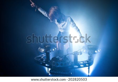 In a nightclub, under the light of the lamps, girl playing on vinyl