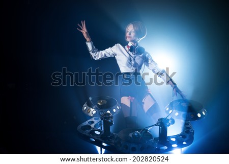 In a nightclub, under the light of the lamps, girl playing on vinyl