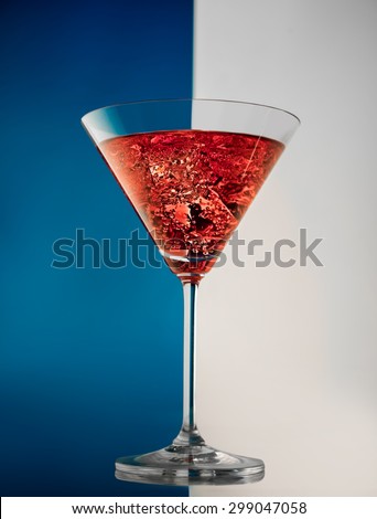 Glass of red martini on a white-blue background with ice