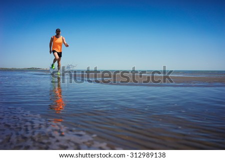 Athlete in sportswear running along the lake shore