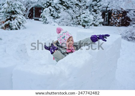 happy child girl plays snowballs in snow castle in winter garden