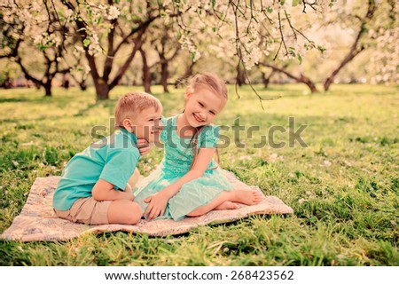 happy brother and sister are playing in spring apple garden