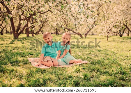 happy brother and sister are playing in spring apple garden