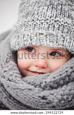 cute smiling baby girl winter close up portrait in warm knitted hat and scarf