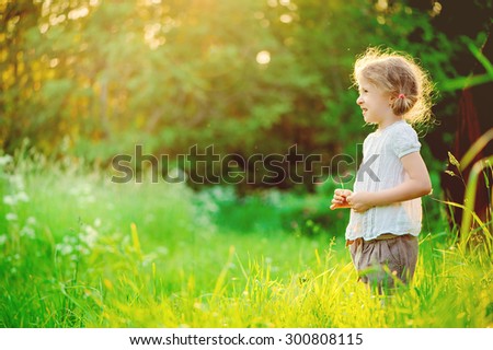happy child girl in white shirt dreaming on the walk on summer field