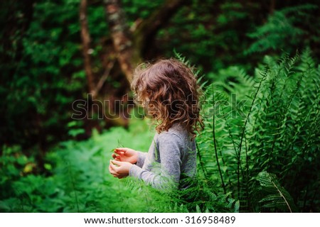 child girl on the walk in summer forest near ferns