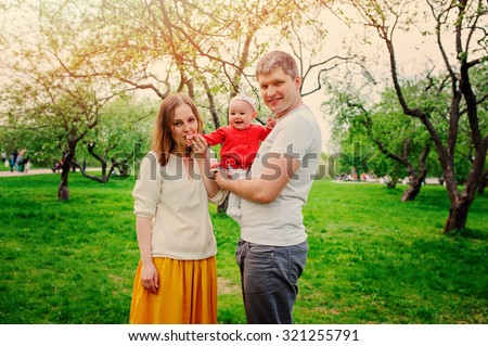 lifestyle capture of happy family spending time together with baby daughter on the walk in spring garden
