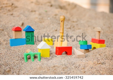 toy house made of colorful wooden bricks in sandbox with shovel