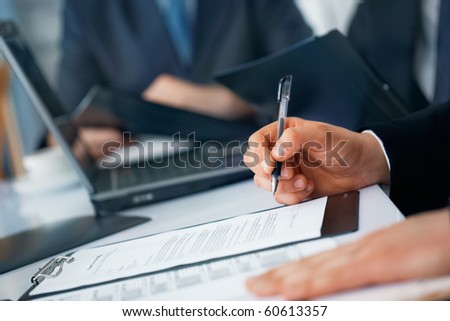 Close-up picture of businessman\'s hands with pen and documents