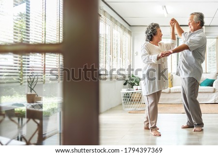 Romantic Asian Senior couple dancing at home. Happy Smiling Grandfather and Grandmother having fun Celebrating in wedding Anniversary day. Elderly man and woman holding hands together, Romance, lover