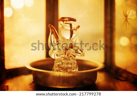 Christmas decoration with angel and candle light. Image toned in vintage warm colors. Selective focus, bokeh lights.