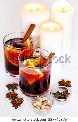 Christmas background with mulled wine, candles and spices such as anise, cardamom, cinnamon over white. Hot mulled wine is great for greeting cozy Xmas concept.