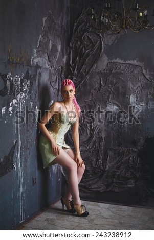 Freaky young female model in vintage clothing wearing corset. Bright pink dreadlocks hairstyle, beauty make up. Dark gothic style.