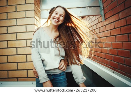 Sunny outdoor portrait of young happy stylish couple having fun. Woman with long hair, laughing. Instagram color style.