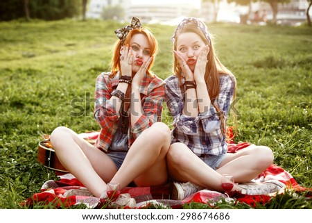 Two Young Hipster Girls Dressed in Pin Up Style Having Fun at a Picnic in the Park in the Sunset