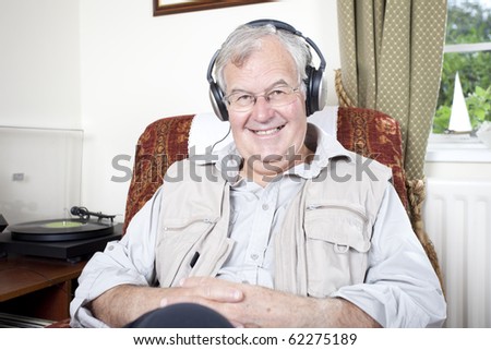 senior citizen listening to vinyl records through headphones