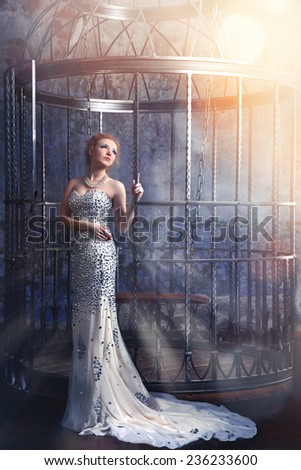 beautiful woman in elegant long dress standing near the cage