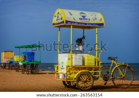 PONDICHERRY, INDIA - FEBRUARY 12, 2013: Unidentified Indian street ice cream vendor with cart on beach