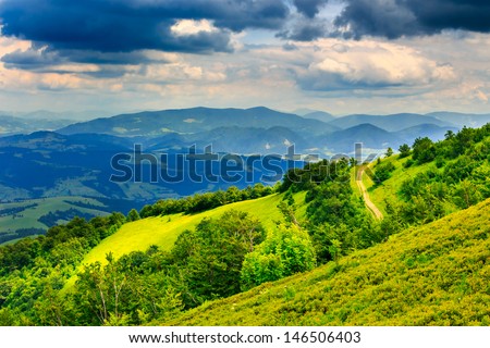 large clearing on the hillside. mountain road passes through a pine forest. sky after a storm with beautiful clouds. high prospect can see the distant mountains