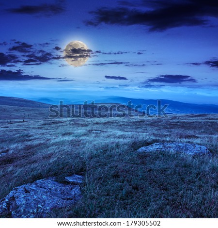 mountain landscape. valley with stones on the hillside. forest on the mountain under the beam of light falls on a clearing at the top of the hill at night in moon light