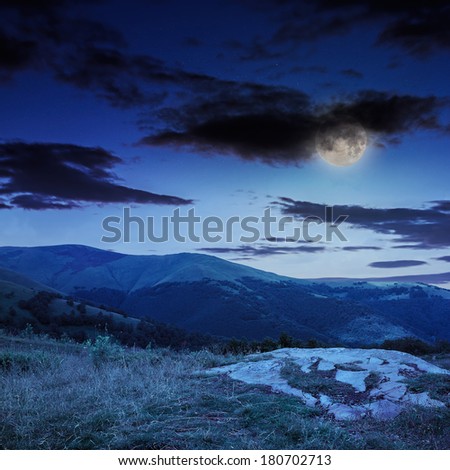 mountain landscape. valley with stones on the hillside. forest on the mountain under the beam of light falls on a clearing at the top of the hill. at night