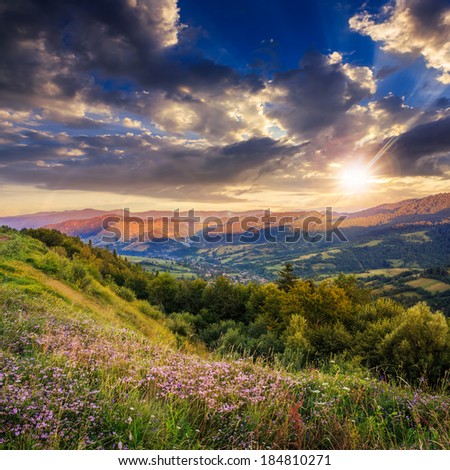 summer landscape. village on the hillside. forest on the mountain light falls on clearing on mountains at sunset