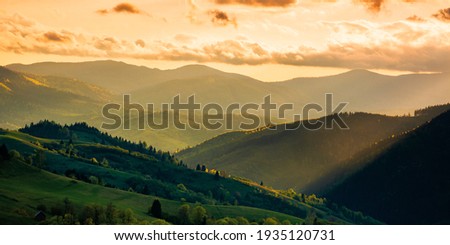 mountainous countryside scenery at sunset. dramatic sky above the distant valley. green fields and trees on the hill. beautiful nature scenery of carpathians