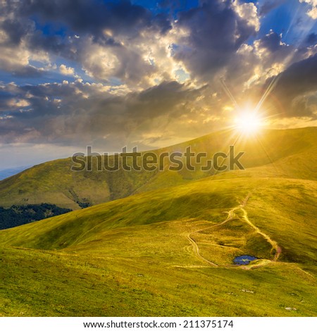 lake near the path in grass at the top of the mountain at sunset
