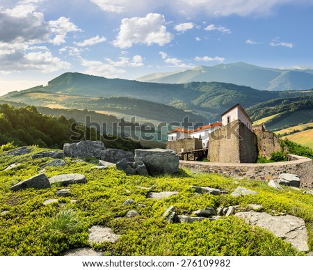 composite mountain landscape with ancient fortress with high stone walls and red roof among the woods and huge boulders on a hillside