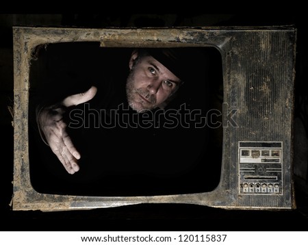 Man behind TV screen. A man behind the TV screen in dark background that wants to handshake the viewers