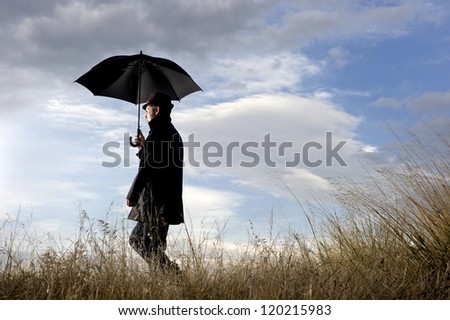 Walking in the countryside A man walking in the countryside alone between dry bushes holding his umbrella