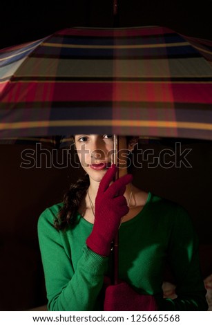 Teenage girl holding an umbrella A beautiful teenage girl holding an umbrella wearing a pair of red knitted gloves and green sweater