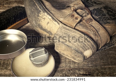 Shoe care. Shoe wax, boot and brushes on wooden surface. Edited image with vintage effect