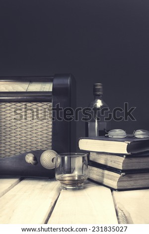 Composition with vintage items on table Vintage radio, books, glasses and whiskey on wooden surface. Edited image with vintage effect