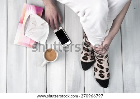 Woman sitting on floor with coffee smartphone and tissue box next to her