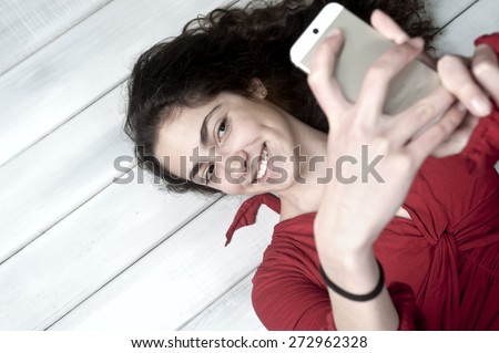 Young female lying on floor taking selfie with her smartphone