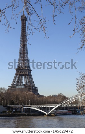 Paris in the early spring. View of the Eiffel Tower from the Seine. In the foreground is slightly blurred branches of the  Platanus trees.