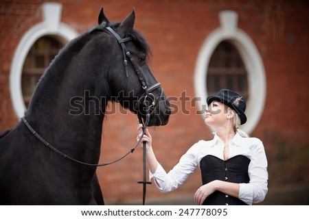 Portrait of the girl and black horse. The girl communicates with a beautiful horse. Equestrian sport.